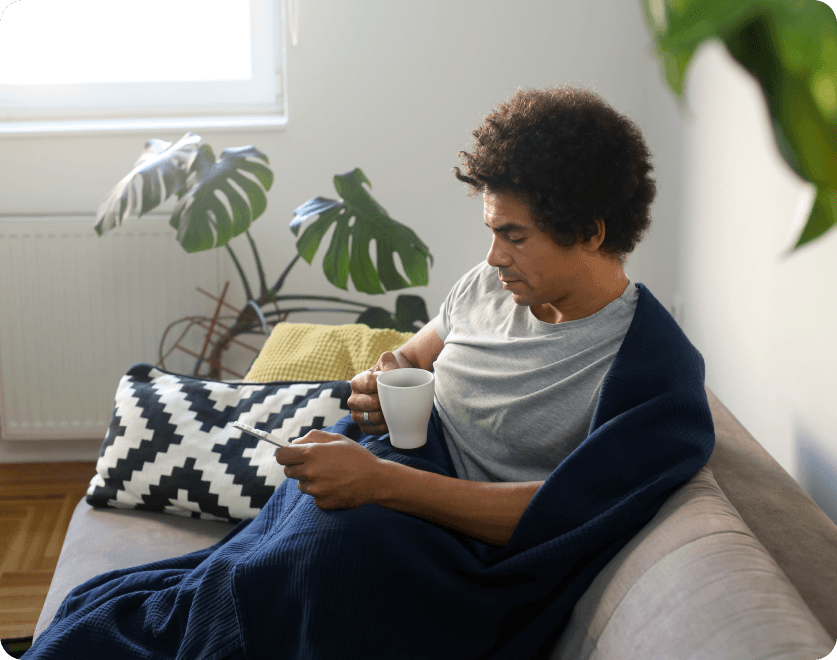 Person drinking tea in a blanket